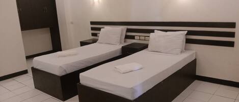 Una habitación de hotel con dos camas individuales, un escritorio pequeño y un armario.