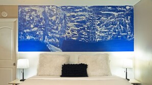 A hotel room with a large bed, two bedside lamps, and a large abstract painting above the bed. - Montrose Stylish Studio! Medical Center 46 (Houston)