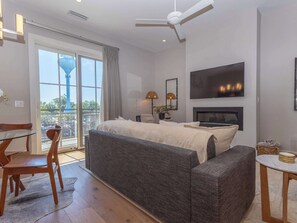 A bedroom with a bed, a sofa, a TV, a ceiling fan, and a balcony with a view.