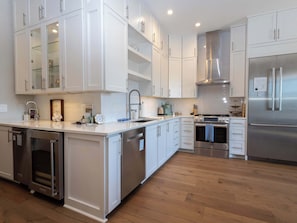 Una cocina moderna con armarios blancos, electrodomésticos de acero inoxidable y suelo de madera.