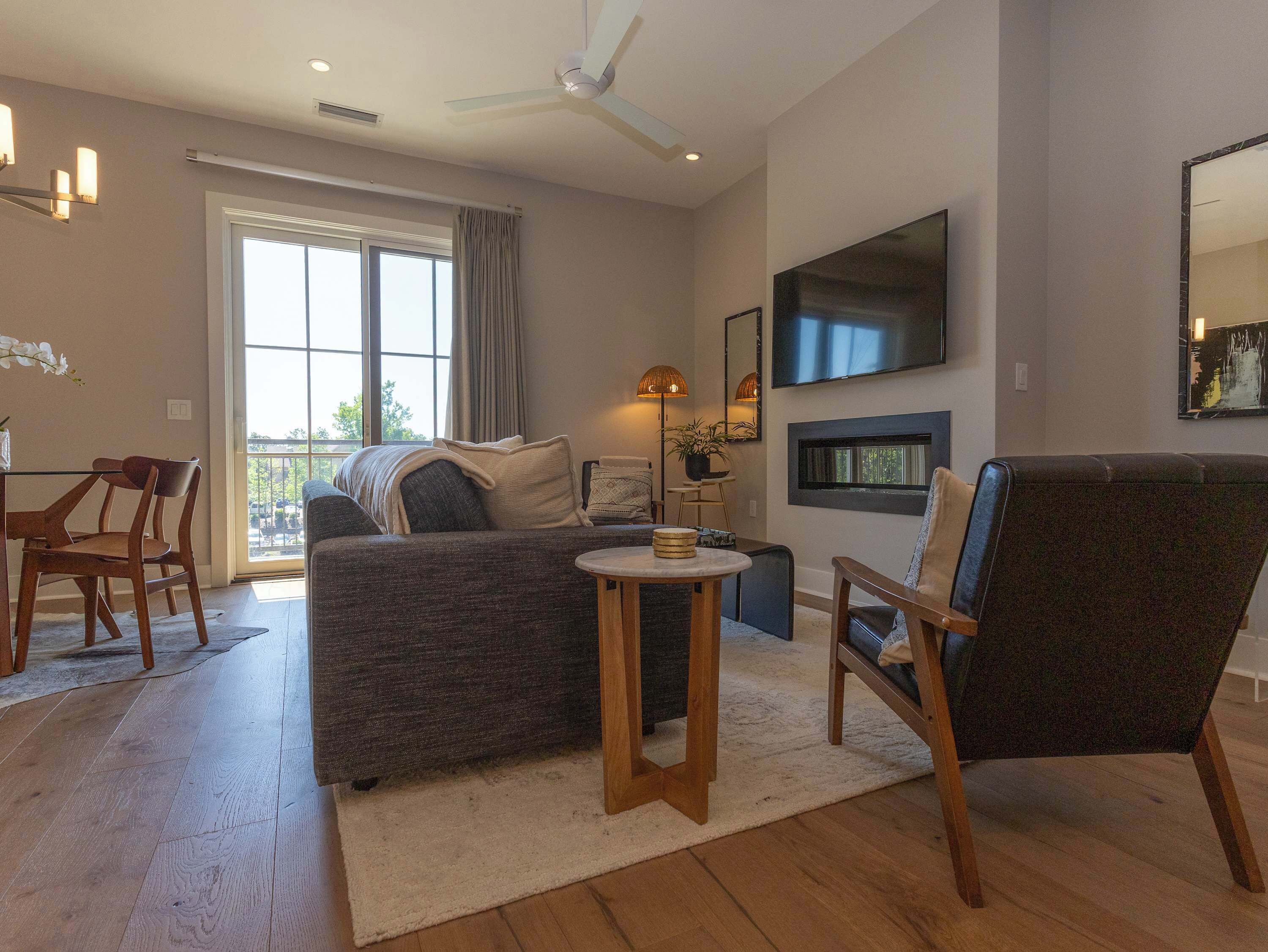 Un salon moderne comprenant un canapé, une table à manger, des chaises, un téléviseur et un ventilateur de plafond.