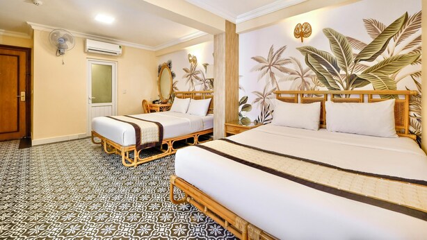 A hotel room with two beds, a large mirror, and a wall mural of tropical plants. - Spring House Hotel (Ho Chi Minh City)