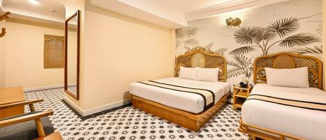 A hotel room with two single beds, a wooden desk, a mirror, and a patterned floor.