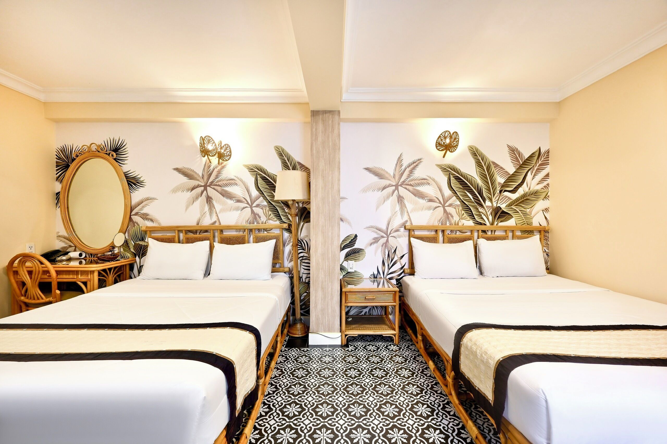 Ett hotellrum med två sängar, en stor spegel, ett sängbord och en vägg med ett tropiskt bladmotiv.