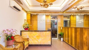 A hotel reception area with a marble counter, wicker furniture, and a chandelier. - Spring House Hotel (Ho Chi Minh City)