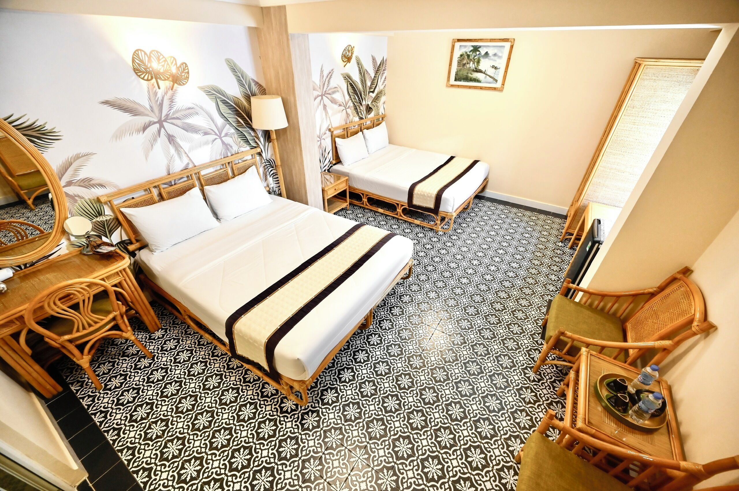 A hotel room with two beds, a sitting area with a chair, a small table, and a decorative mirror.