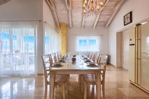 A dining area with a long table set for a meal, wooden chairs, a chandelier, and a clock on the wall. - Villa Lapis with private Pool, Buzet, Croatia (Buzet)