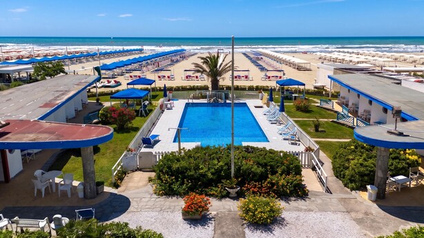 Ein Poolbereich mit freiem Blick auf den Strand, Liegestühle und Sonnenschirme.