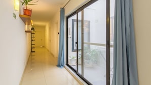 A hallway with a sliding glass door leading to a balcony with potted plants.