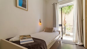A single bed with a white mattress, a brown blanket, and a pillow. A book is placed on the bed.