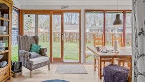A cozy room with a wicker chair, a dining table, and a large sliding glass door leading to a garden. - Nice home in Børkop with Wi-Fi (Børkop)