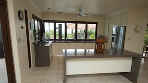 A modern kitchen with a central island, large windows, and a refrigerator.