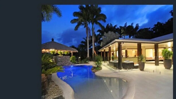 A modern resort with a swimming pool, a covered outdoor area, and palm trees.