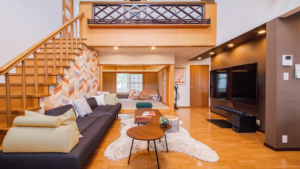 A spacious living area with a sofa, a coffee table, and a TV. A staircase leads to an upper level. - THE BLAUBAUM TOYA (Toyako)