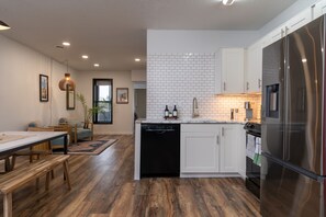 Una cocina moderna con armarios blancos, un refrigerador de acero inoxidable y un lavavajillas.