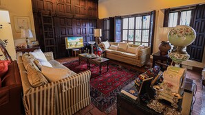 A cozy living room with a sofa, armchairs, a coffee table, and a television. - Hotel Casa Bansley (Antigua Guatemala)