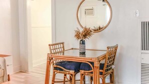 Un coin repas avec une table en verre, des chaises en osier et un vase contenant des fleurs séchées.