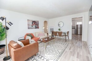 Uma sala de estar moderna com sofá, mesa de centro e área de jantar.