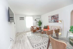 A modern living room with a sofa set, a coffee table, and a dining area with chairs and a glass table.