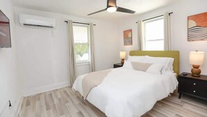 Ein Schlafzimmer mit Bett, Nachttischlampen, Deckenventilator und Klimaanlage.