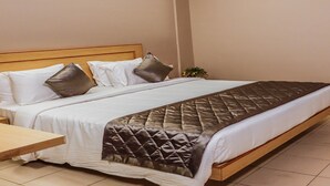 Ein ordentlich bezogenes Bett mit gestepptem Kopfteil, einem Nachttisch und einer an der Wand montierten Klimaanlage.