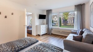 Une chambre à coucher comprenant un lit, un canapé, une télévision et une fenêtre donnant sur l’extérieur.