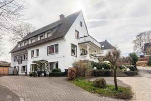 A two-story house with a sloped roof, a front porch, and a paved driveway. - Ferienwohnung "Kupferkessel" (Eslohe)
