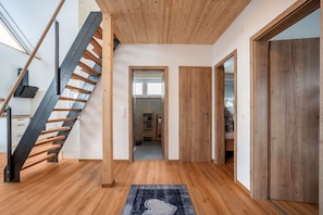 A modern interior with a wooden staircase, a hallway leading to a room, and a door. - Holiday Home 'Tiny Time' with Private Terrace, Shared Garden and Wi-Fi (Krumbach)