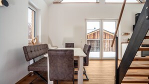 A modern interior with a dining area, a staircase, and a view of the outside.