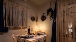 Uma área de jantar com uma mesa posta para dois, uma garrafa de vinho e objetos decorativos.