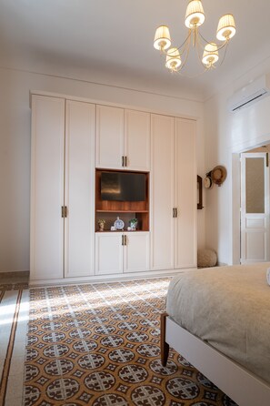 A bedroom with a bed, a wardrobe, a television, and a patterned floor. - Casa Makrame in Syracuse (Syracuse)