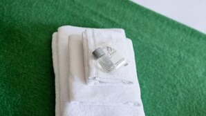 Une serviette blanche, une bouteille de shampoing Coccole et un savon, le tout posé sur une surface verte.