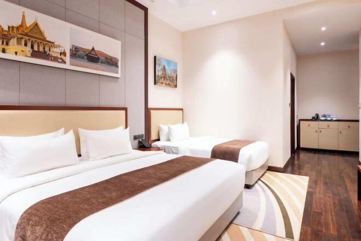 Ein Hotelzimmer mit zwei Betten, einem Schreibtisch und einem Schrank.