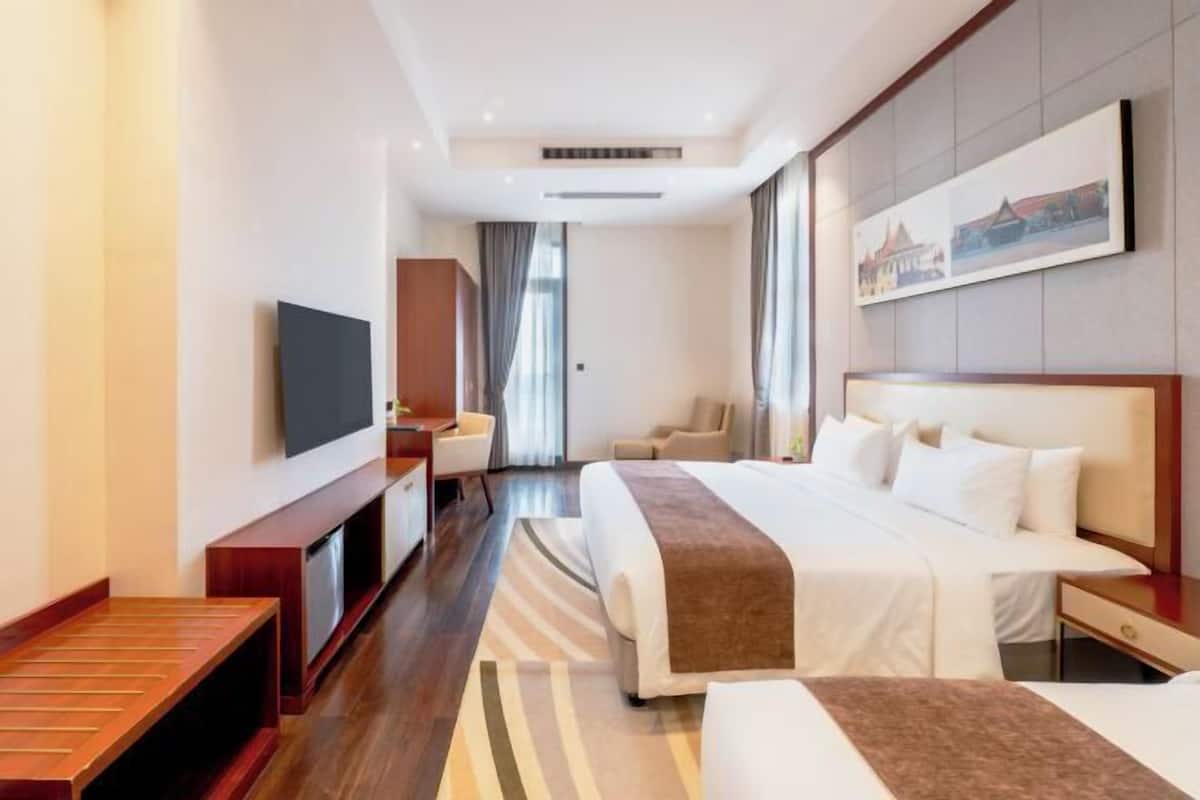 Een hotelkamer met een groot bed, een televisie, een bureau en een stoel.