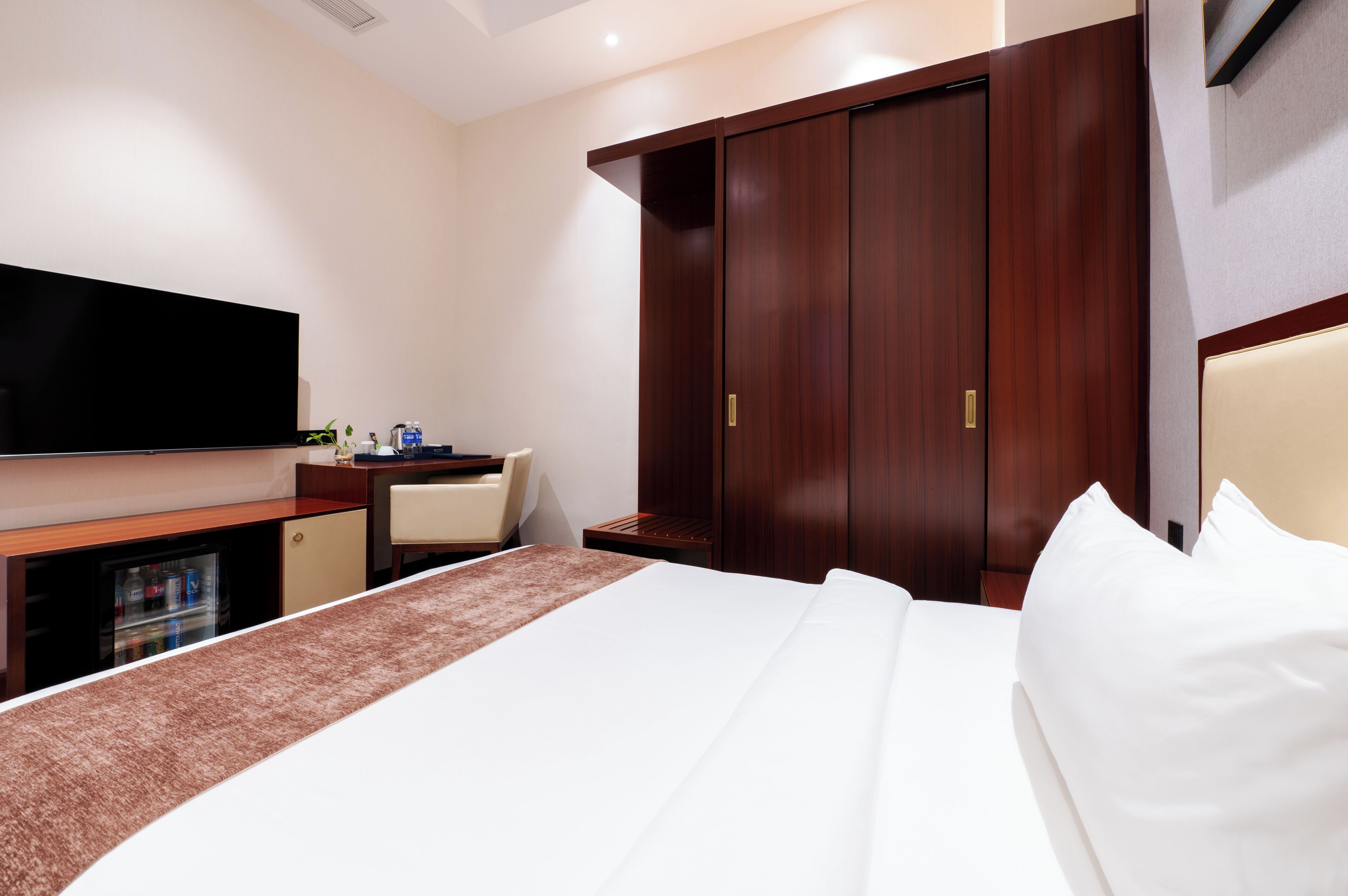 Una habitación de hotel con cama, televisión, escritorio, silla y armario.
