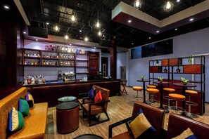 A bar area with a counter, shelves of bottles, and stools. - V V Hotel Battambang (Battambang)