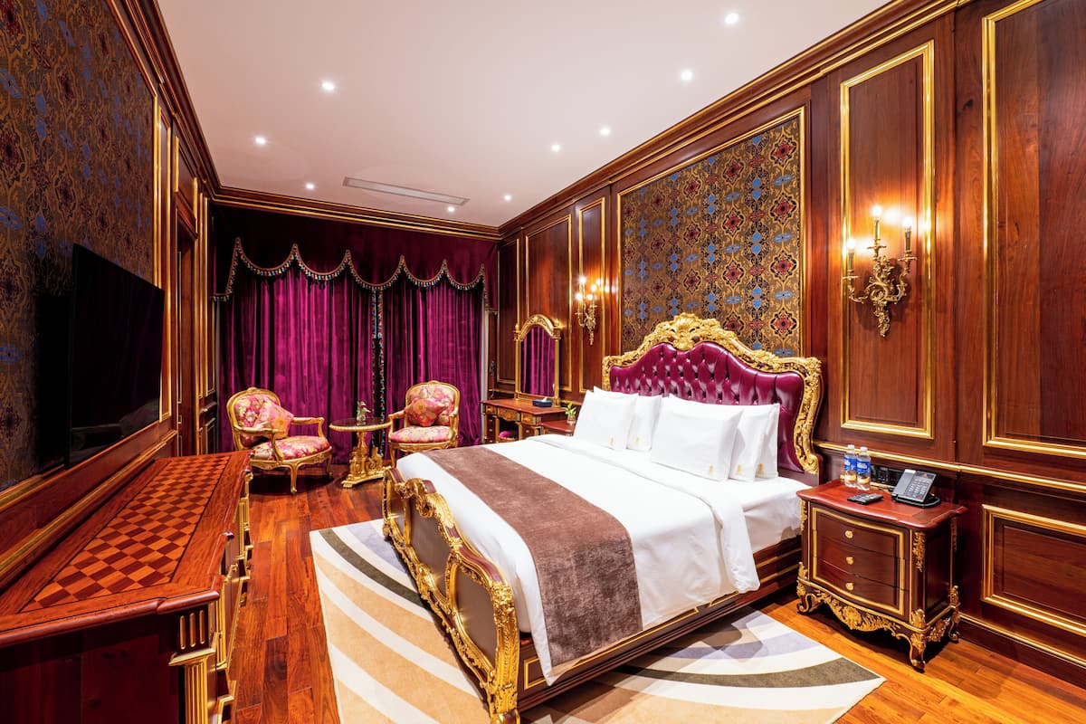 Een luxe slaapkamer met een groot bed, een kaptafel, een bureau en een televisie.