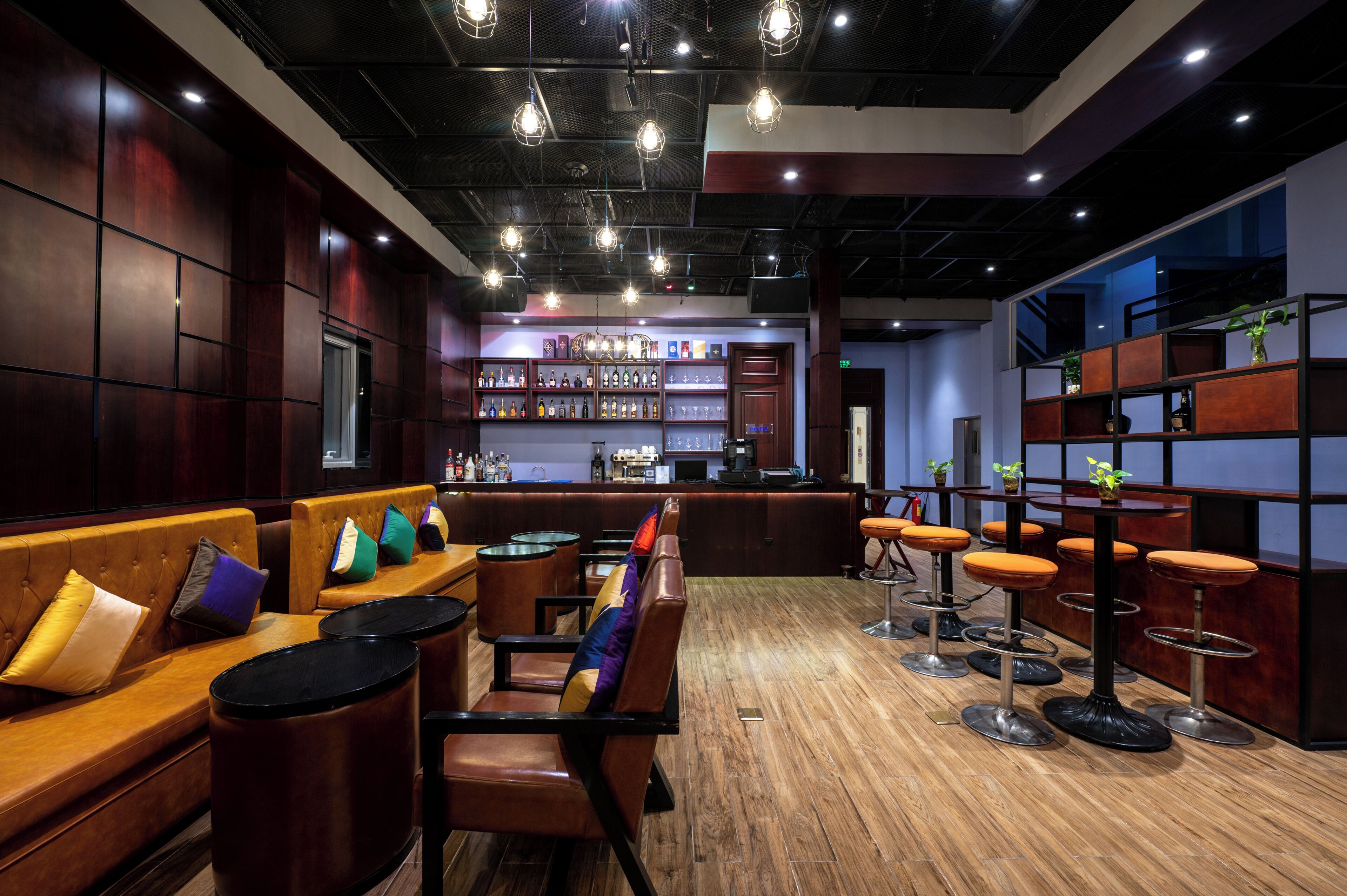 A bar area with wooden flooring, leather seating, and bar stools.
