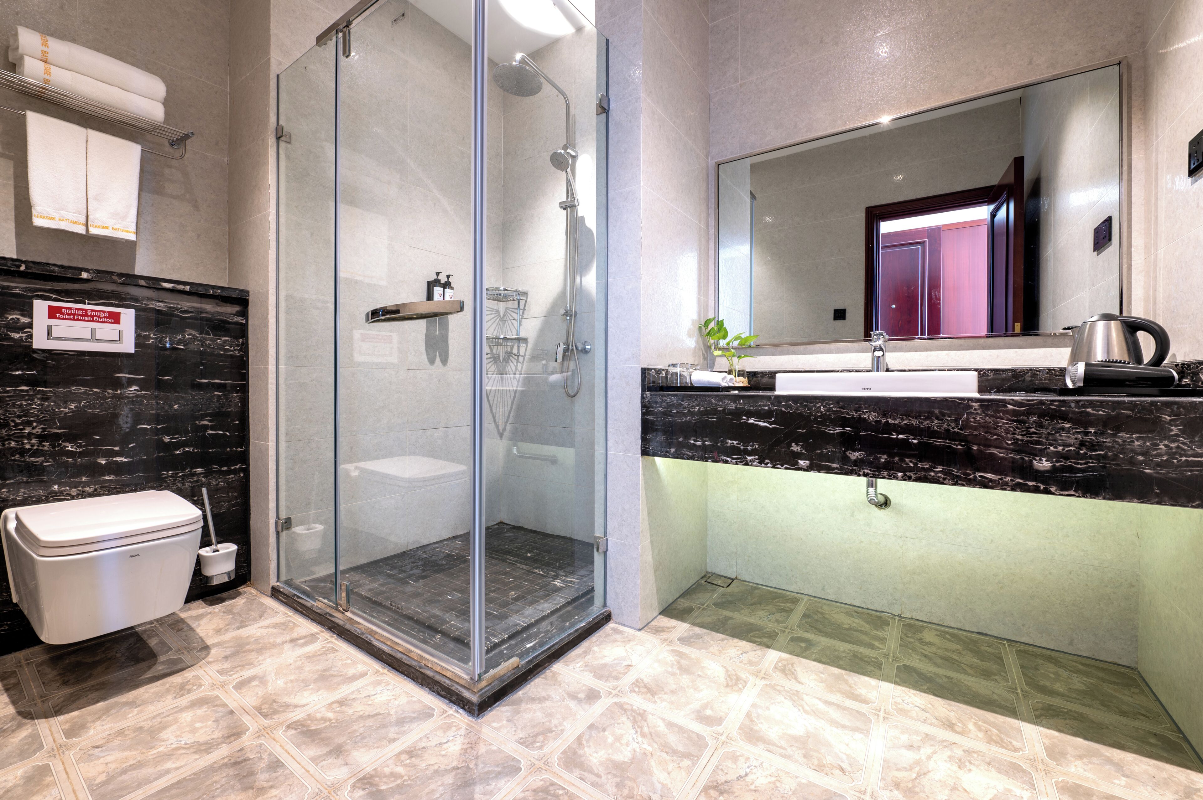 A modern bathroom with a glass-enclosed shower, a marble sink, and a large mirror.