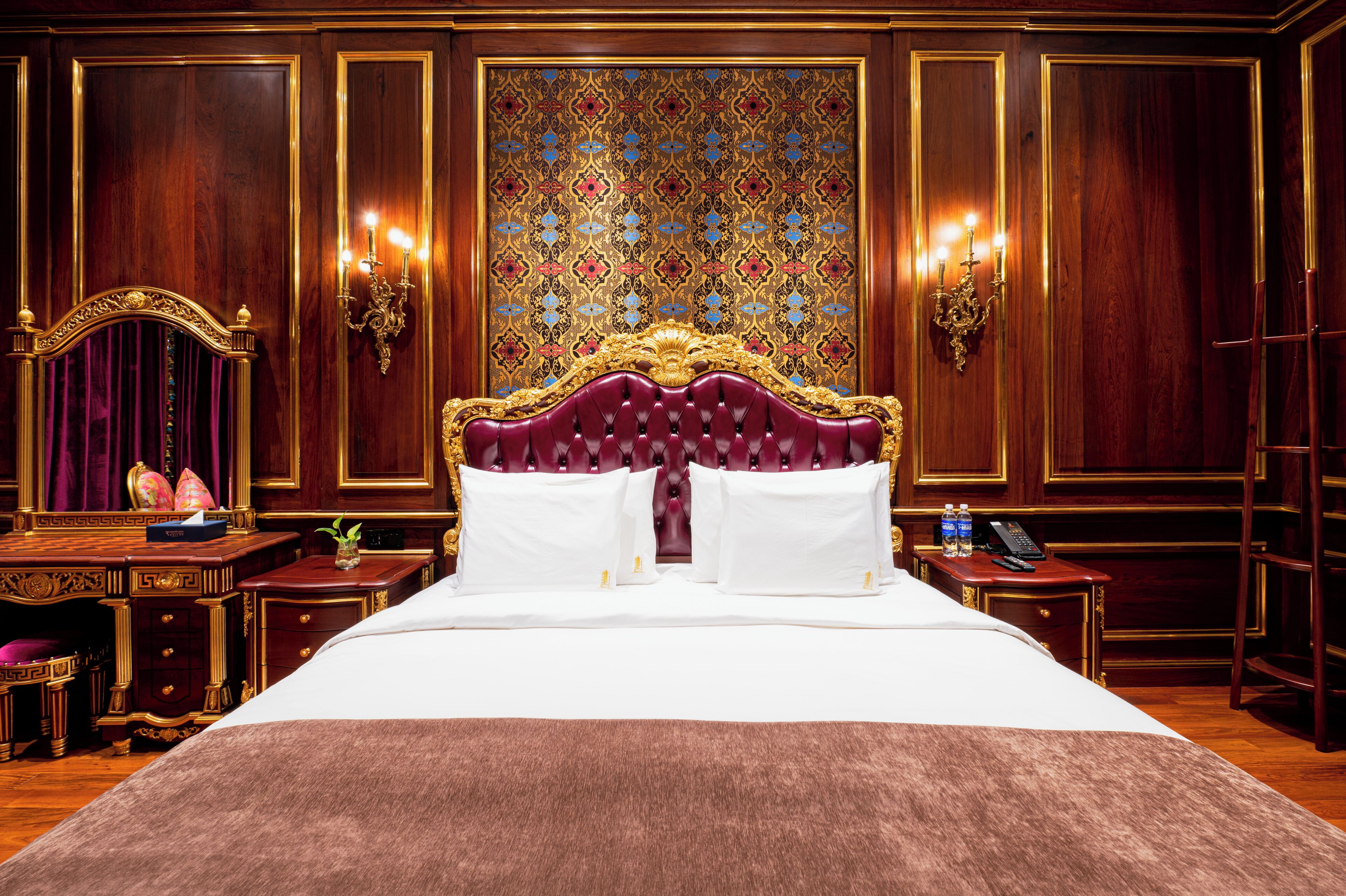 Una lujosa habitación de hotel con una cama grande, un cabecero ornamentado y un panel decorativo en la pared.