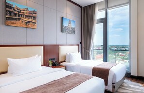 A hotel room with two beds, a large window with a city view, and two framed pictures on the wall. - V V Hotel Battambang (Battambang)