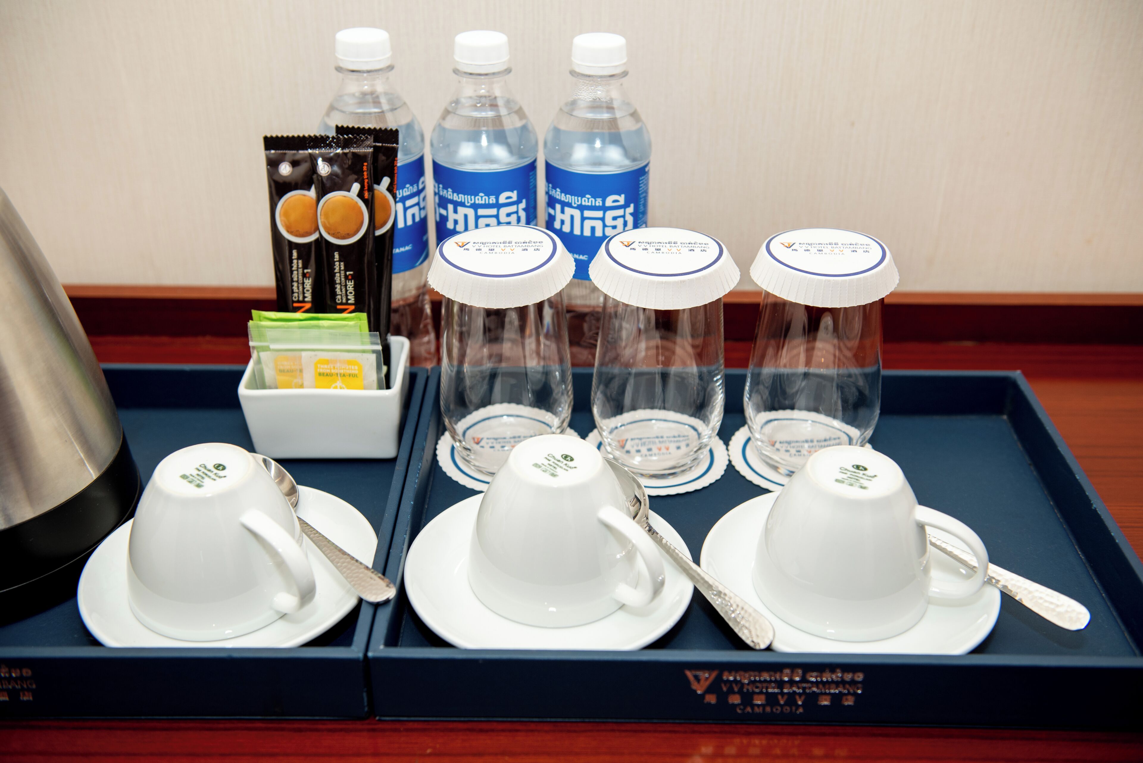 A tray with tea cups, a teapot, and bottled water.