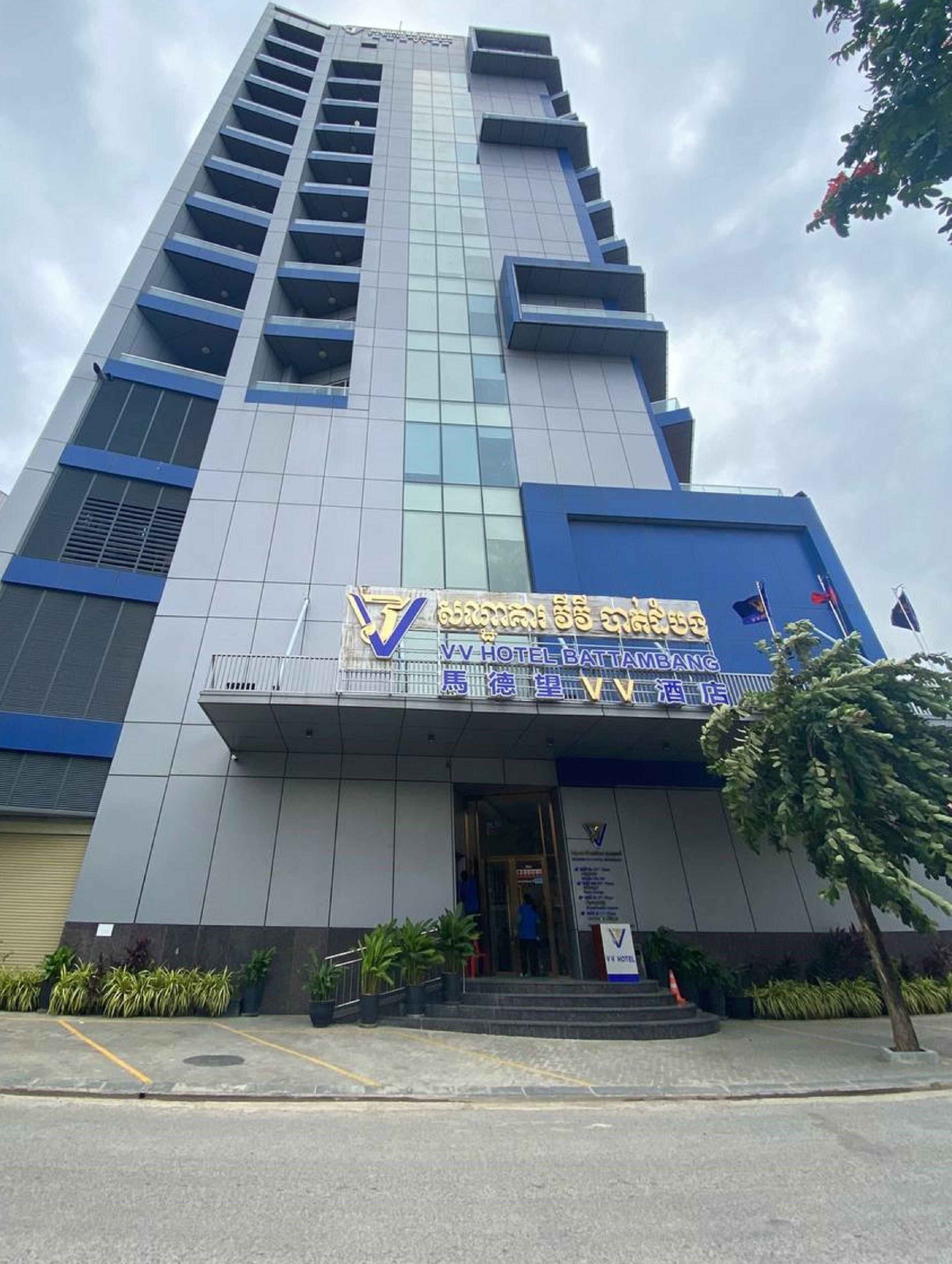 Un edificio de hotel alto de diseño moderno, con un letrero llamativo del VV Hotel Battambang.