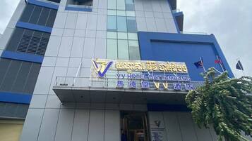 Un edificio de hotel alto de diseño moderno, con un letrero llamativo del VV Hotel Battambang.