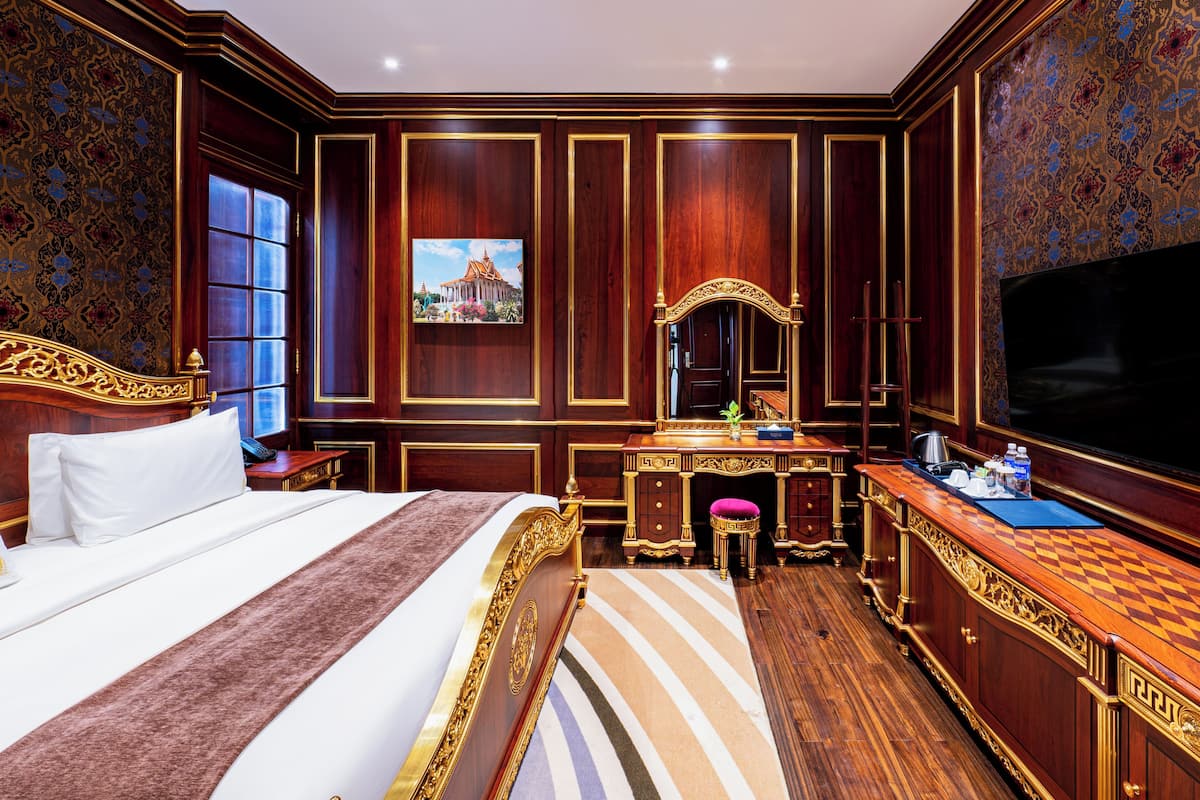 Een luxe hotelkamer met een groot bed, een kaptafel met spiegel, een televisie en een bureau met stoel.
