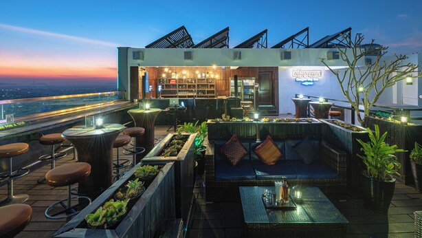 Un bar situé sur le toit, avec des places assises, un espace bar et une vue sur le panorama urbain.