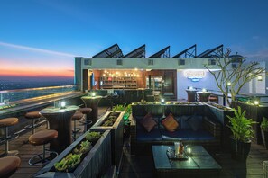 Um bar no terraço com assentos, área de bar e vista para o horizonte da cidade.