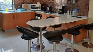 A kitchen with a central island, bar stools, a microwave, a stove, and a sink. - Cosy apartment unit in a triplex at less 100m from the beach with a common pool (Flic en flac)