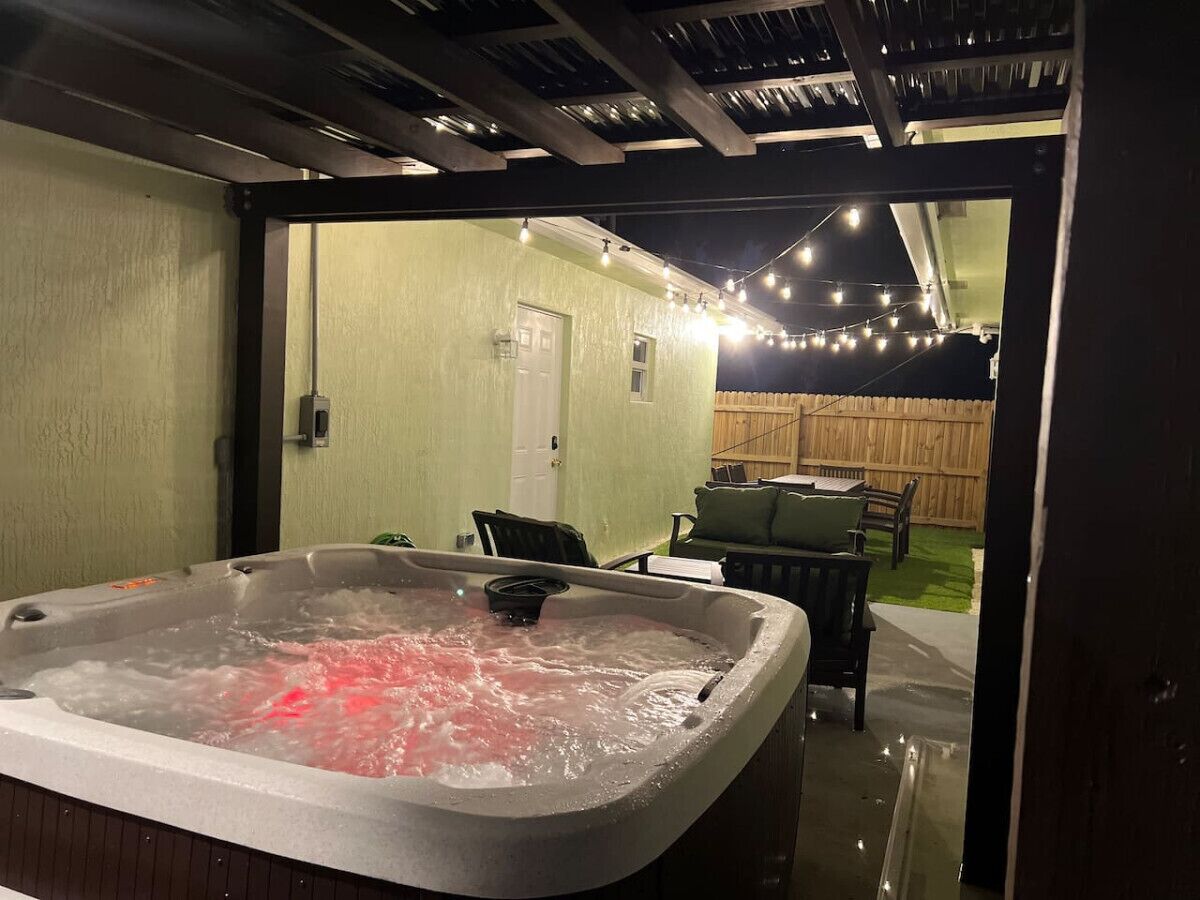 Een hottub in een overdekte buitenruimte met een houten terras en stoelen.