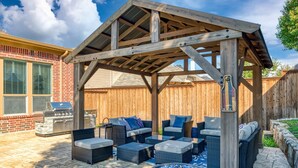 Un patio couvert avec des meubles d’extérieur, un barbecue et un foyer.